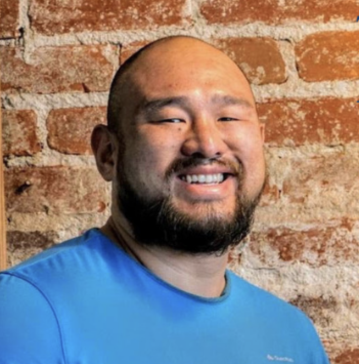 headshot of a guy with a brick wall as background