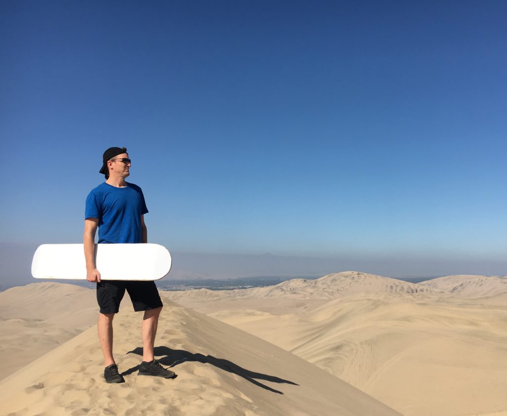 man standing in the desert holding a sand board