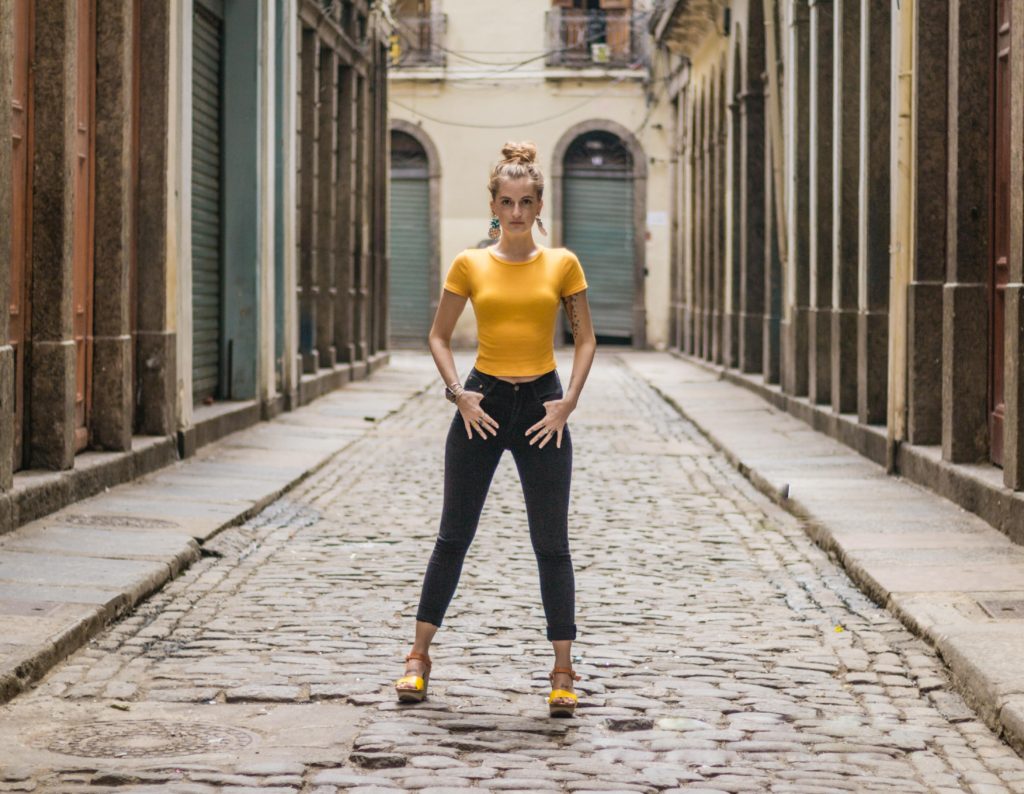 woman in yellow shirt standing in the middle of the road