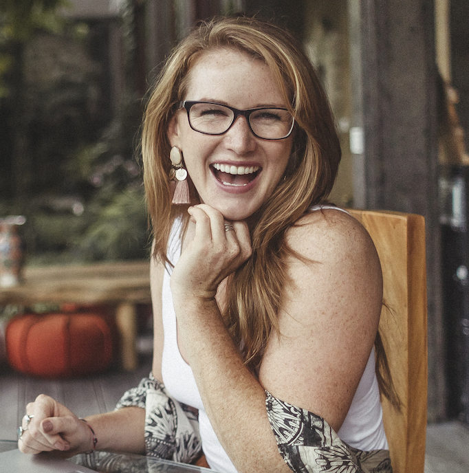 red haired woman with eyeglasses looking happy