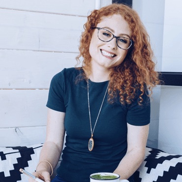 woman with curly red hair sitting on a couch