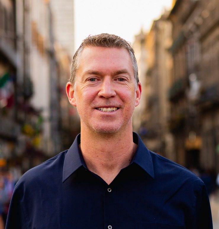 headshot of man wearing navy shirt