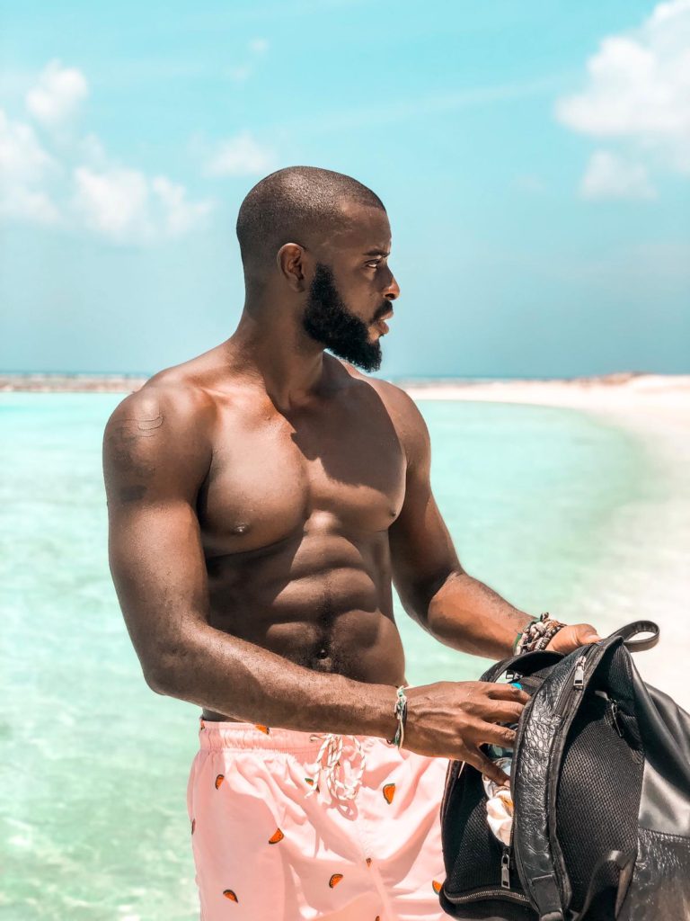 man at the beach holding a backpack
