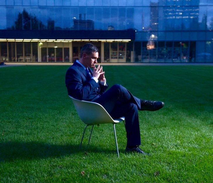 man seating on a chair in the middle of a field