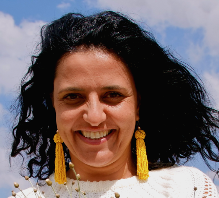 headshot photo of a woman smiling with yellow earrings