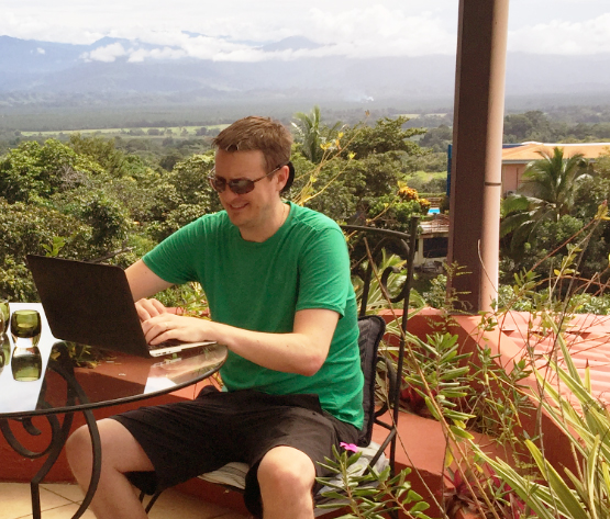 guy in green shirt happily working on his laptop